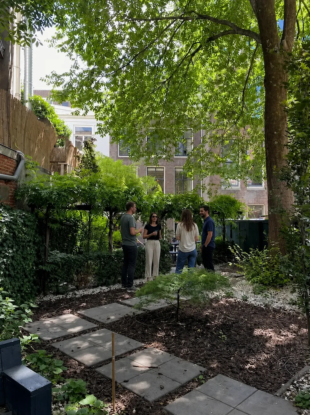 The Xeco Labs team talking in the building's garden on a summer afternoon.
